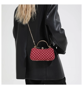 Rear view of a model wearing a red polka dot box bag with gold chain strap and metal handle