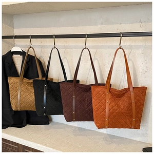Close-up of quilted tote bags in camel, black, brown, and orange with metal rivet details