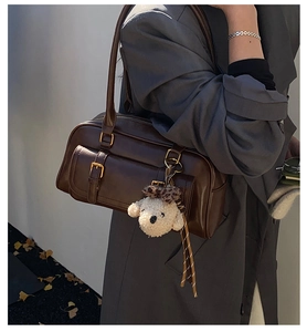 Detail of dark brown retro bowling bag with glossy leather and cute puppy charm accessory