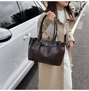 Détail d'un sac cabas vintage marron foncé avec ceinture décorative et boucle argentée