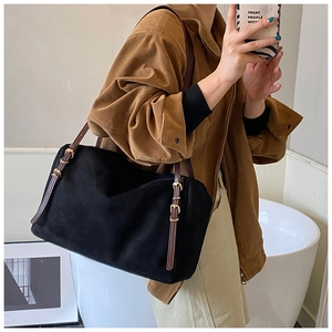 Detail of suede tote bag with adjustable brown leather straps and gold buckle accents