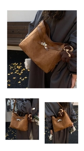 Close-up of caramel suede tote bag featuring a metal turn-lock and knit bear charm