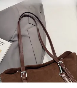 Close-up of brown suede tote bag with adjustable shoulder strap and silver buckle