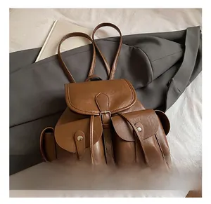 Close-up of caramel brown leather backpack with silver metal buckles and side pockets