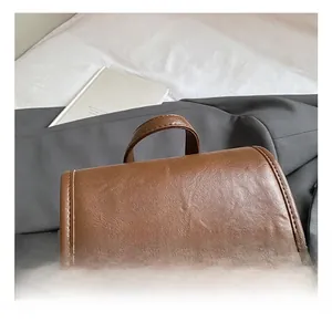 Detail shot of brown leather backpack featuring a sturdy top handle and fine stitching