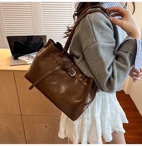 Detail of vintage brown leather tote bag showing silver buckle and shoulder strap