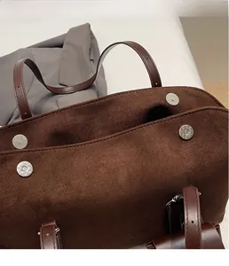 Close-up of magnetic buckle and dark brown suede texture on this retro tote bag