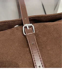 Close-up of silver square buckle and brown suede texture on retro tote shoulder bag