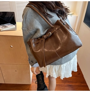 Detail of dark brown leather tote bag with silver buckle and stylish shoulder strap