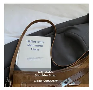 Detail of adjustable leather strap and silver metal buckle on brown vintage suede bag
