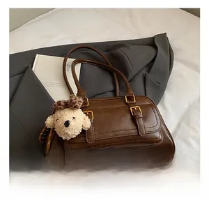 Detail of dark brown leather bowling bag with plush puppy charm on a stylish blazer