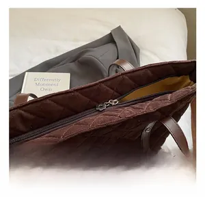 Close-up of brown quilted tote bag with silver flower zipper and leather handles