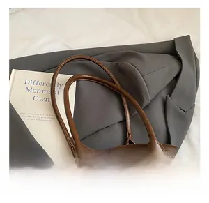 Detail of dark brown leather Boston bag with sturdy handles and gold metal hardware