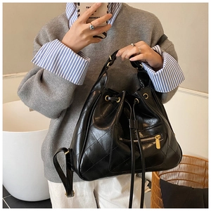 Quilted black bucket bag with gold hardware and drawstring detail shown on model