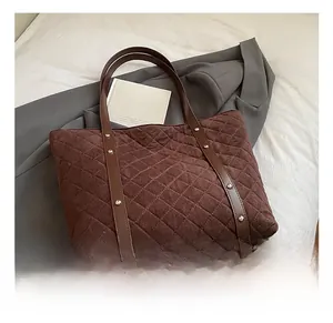 Detail of brown quilted tote bag showing suede texture and leather straps with rivets