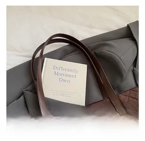 Detail of brown quilted tote bag with suede texture and dark leather handle accents