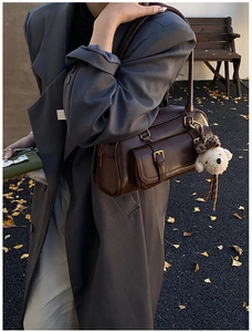 Detailed outdoor shot of a vintage dark brown Boston shoulder bag with a plush bear charm