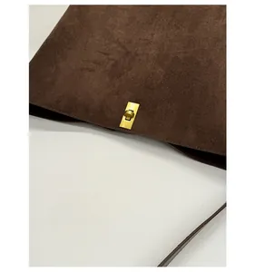 Detail of dark brown suede shoulder bag with durable gold rectangular twist lock hardware