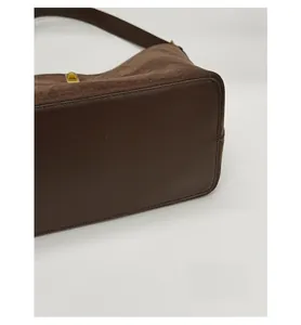 Detail view of the reinforced base and leather splicing on the brown suede tote bag