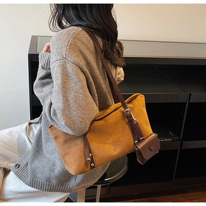 Detail of a large mustard suede tote bag with brown leather handles and a side pouch