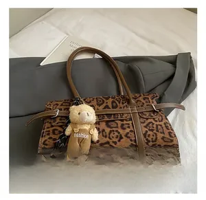Détail du sac Boston à motif léopard avec bordure en cuir et joli porte-clés ours