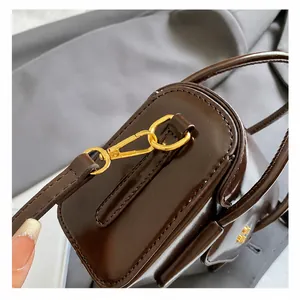 Detail shot of vintage dark brown glossy leather bag with gold lobster clasp and fine stitching