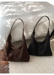 Close-up of vintage suede hobo bags in dark brown and black with vertical stitching