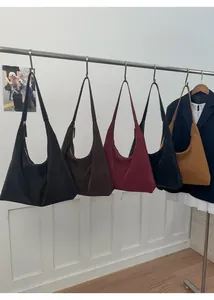 Five assorted colors of suede hobo shoulder bags displayed on a wooden floor background