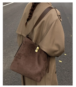 Detail of dark brown suede tote bag with golden metal buckle clasp on leather strap