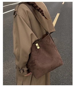 Detail of dark brown suede bucket bag with gold twist lock and leather shoulder strap