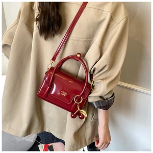 Glossy red faux leather mini crossbody bag with gold hardware and cherry charm detail