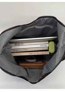 Top view of large suede tote bag interior with striped lining and daily essentials
