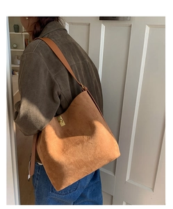 Detailed view of brown suede bucket bag with gold twist lock and long shoulder strap