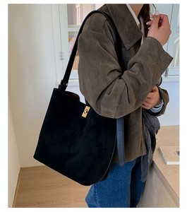Close-up of black suede tote bag featuring a minimalist gold metallic clasp detail