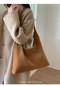 Detail view of large brown suede shoulder bag featuring vertical stitching and wide strap