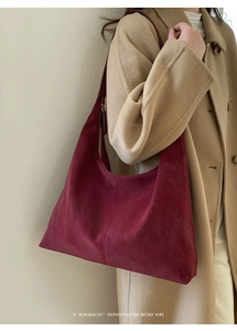 Detail of deep red retro suede tote with contrast stitching on camel wool coat