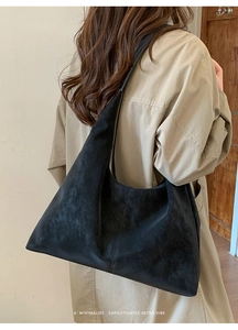 Detail of black suede hobo bag showing soft texture and large capacity on model
