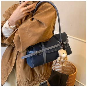 Détail du sac Boston en toile bleu marine avec brides en cuir et breloque ours