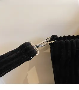 Detail of silver metal hook and black corduroy texture on large tote bag shoulder strap