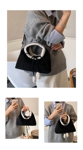 Detail of suede bucket bag featuring white faux fur trim and plush pompom drawstring