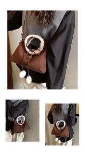 Close-up of brown suede bucket bag with white fleece trim and decorative pom-poms
