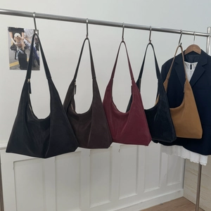 Collection of large suede hobo shoulder bags in five colors hanging on a minimal rack