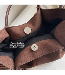 Detail of magnetic snap closure and soft suede texture on vintage brown tote bag