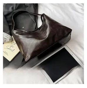 Vue de dessus d'un grand cabas en cuir marron foncé avec tablette et accessoires sur tissu