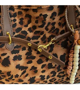 Detail of leopard print suede tote showing golden hardware and decorative beads