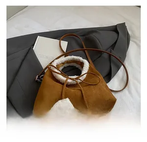Détail du sac seau en daim marron avec bordure en fausse fourrure blanche et pompons