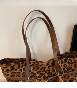 Detail of leopard print tote bag with brown leather straps and gold metal hardware