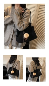 Detail of black faux suede tote bag with plush sheep charm and woven strap detail