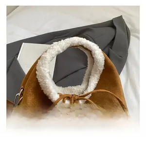 Détail du sac seau en daim caramel avec poignée en polaire blanche et fermoirs métalliques