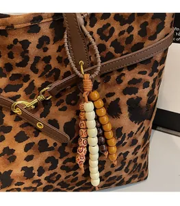Detail of leopard print suede tote bag featuring a wooden bead charm and gold hardware
